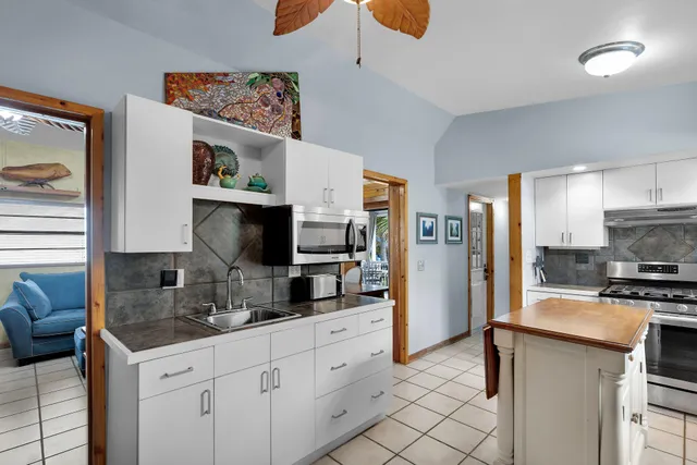 a kitchen with stainless steel appliances a stove top oven a sink a refrigerator and cabinets