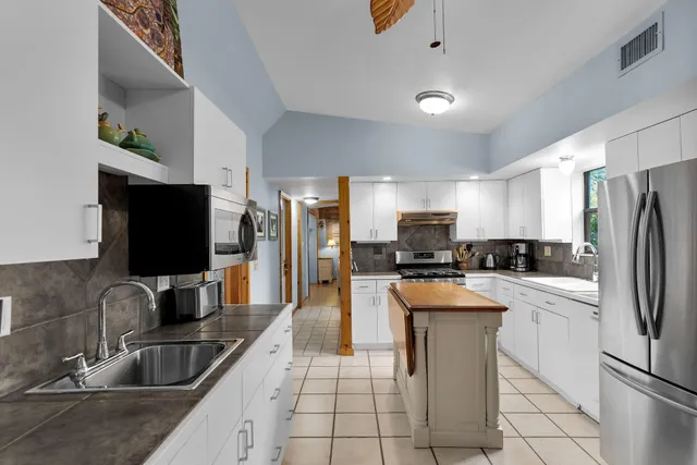 a kitchen with stainless steel appliances granite countertop a sink refrigerator and microwave