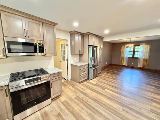 a kitchen with stainless steel appliances kitchen island granite countertop a stove a refrigerator and a microwave