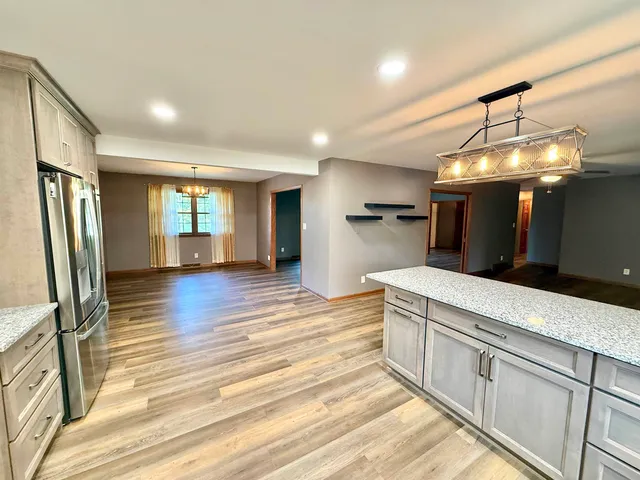 a kitchen with stainless steel appliances granite countertop a refrigerator a stove and a wooden floors