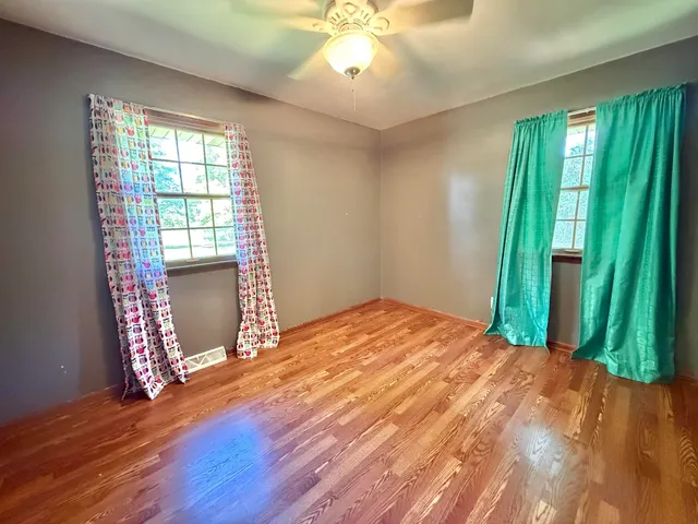 a view of an empty room with a window and wooden floor