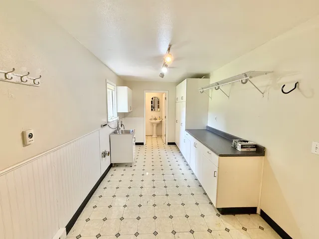 a hallway with white cabinets and wooden floor