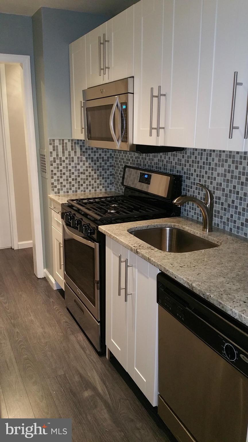 2401 H Street Northwest, Unit 904 Washington, DC 20037 - Photo 7 of 25 a kitchen with granite countertop a stove sink and cabinets