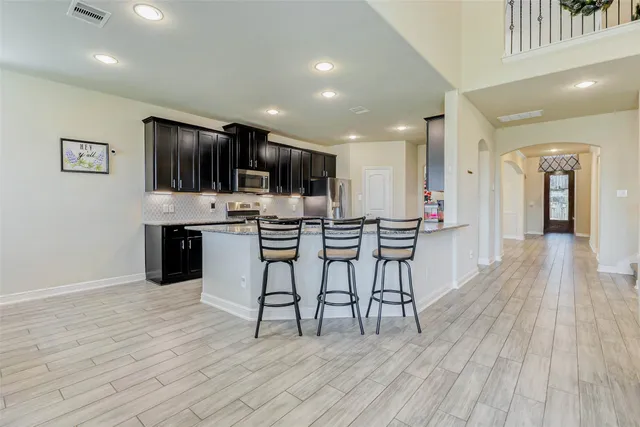 a open kitchen with stainless steel appliances granite countertop a stove top oven a sink dishwasher and a refrigerator with wooden floor