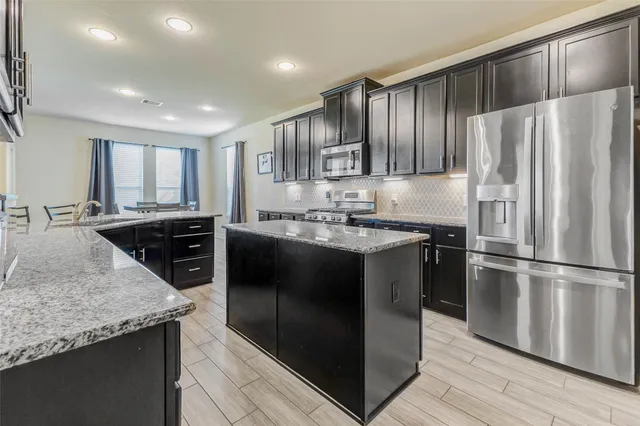 a kitchen with kitchen island granite countertop a sink appliances and cabinets