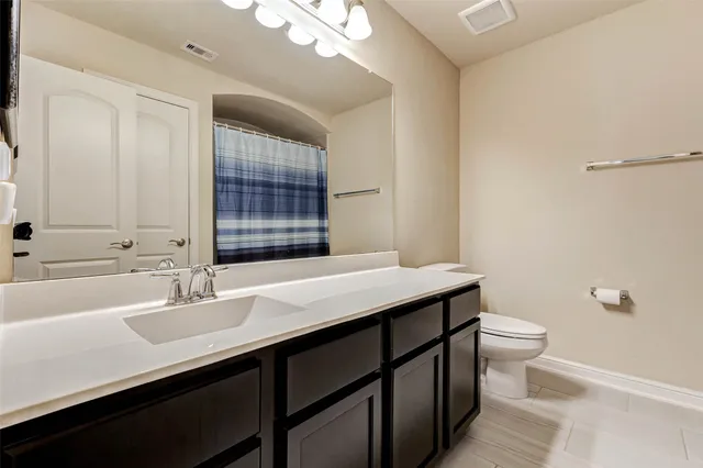 a bathroom with a sink a toilet a mirror and a window