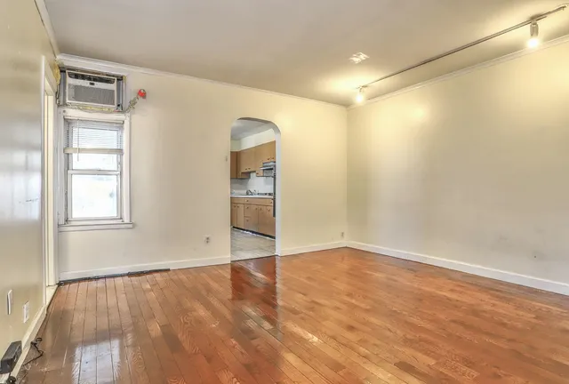 an empty room with wooden floor closet and windows