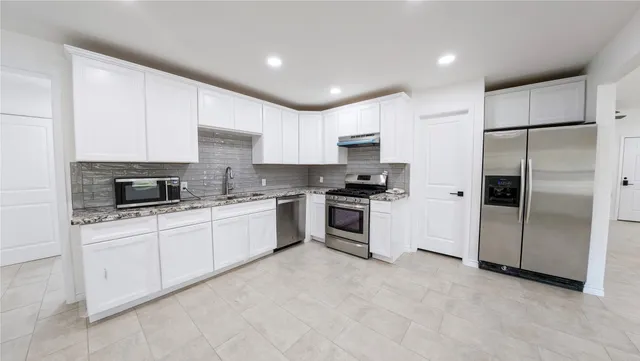 a kitchen with a refrigerator a sink and a stove top oven