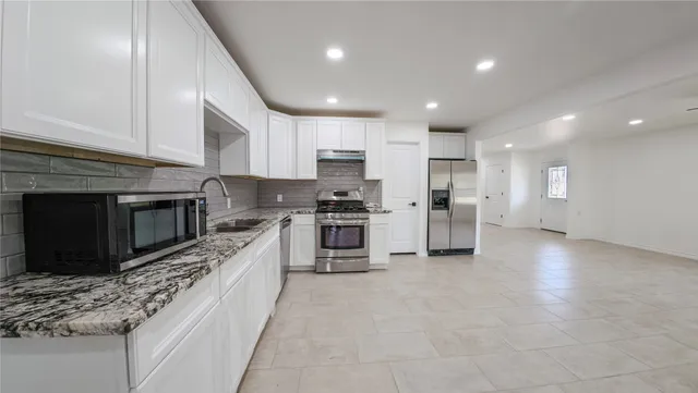 a large kitchen with stainless steel appliances kitchen island granite countertop a stove a sink and a microwave