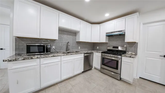 a kitchen with stainless steel appliances granite countertop a stove sink and cabinets