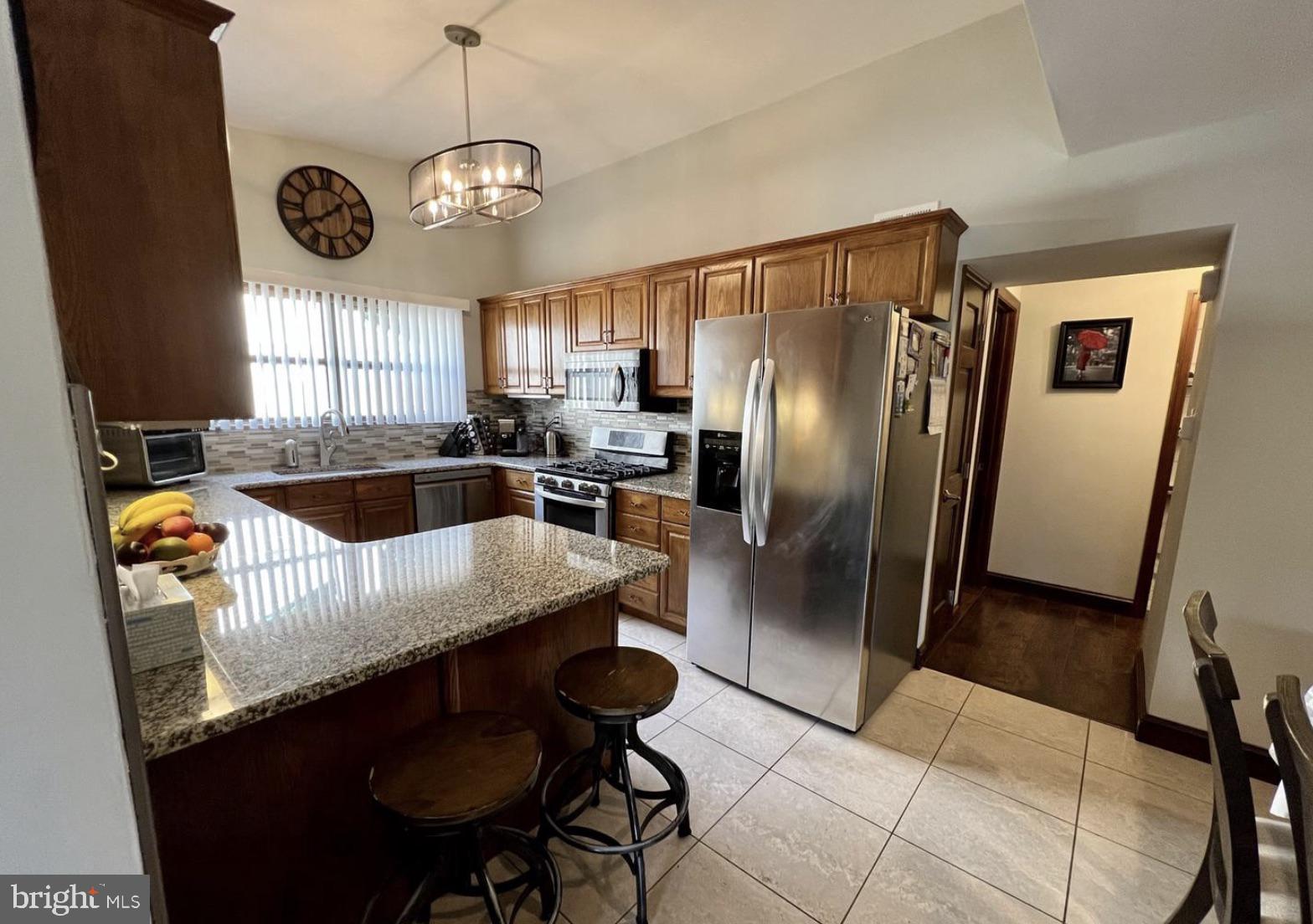 52 Sandpiper Drive Voorhees, NJ 08043 - Photo 8 of 26 a kitchen with stainless steel appliances granite countertop a refrigerator a sink dishwasher a dining table and chairs with wooden floor