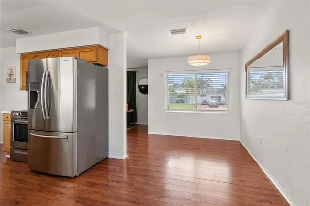 a view of a room with wooden floor fridge and a window