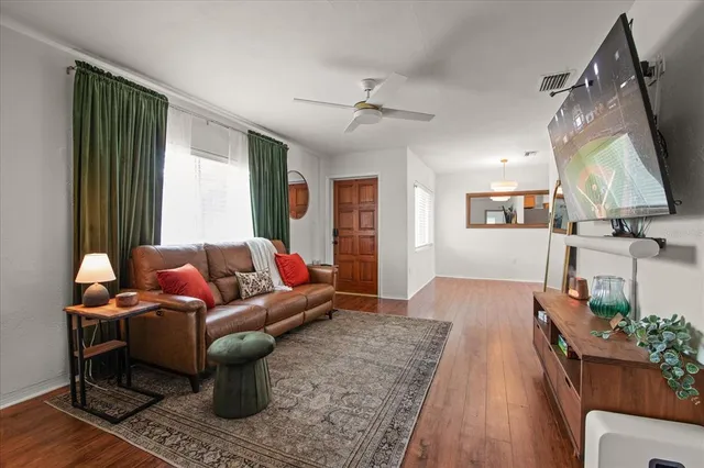 a living room with furniture a large window and wooden floor