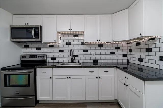 a kitchen with white cabinets and appliances