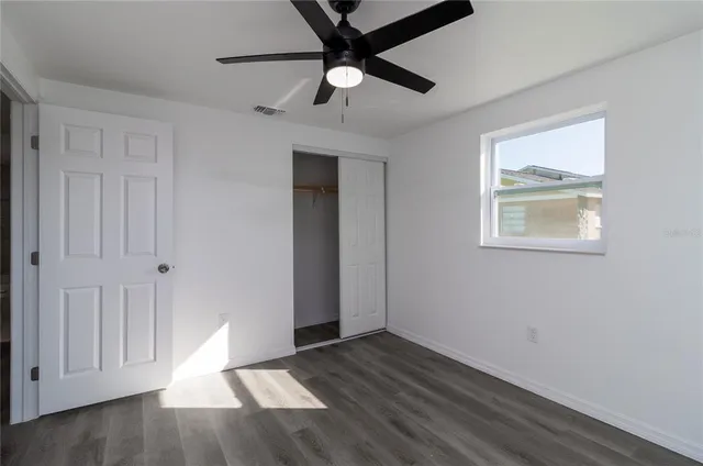a view of an empty room with a window and wooden floor