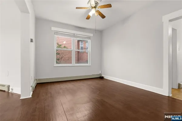 an empty room with wooden floor chandelier fan and windows