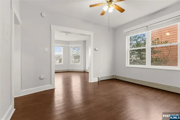 an empty room with wooden floor and windows
