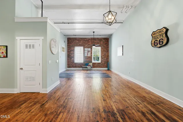 a view of a hallway with wooden floor and a kitchen space