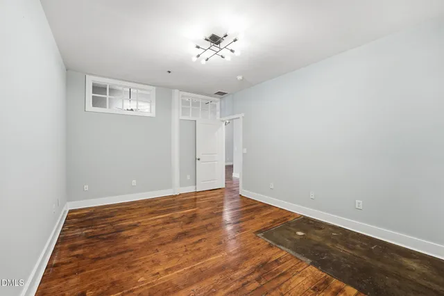 an empty room with wooden floor and a ceiling fan