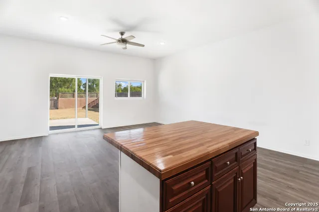 an empty room with wooden floor and fan