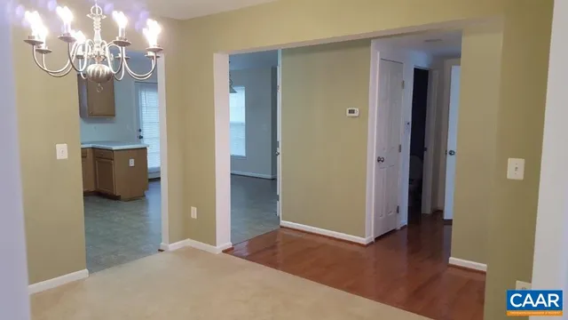 a view of a livingroom and a kitchen space with wooden floor