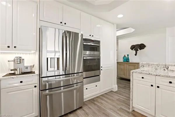 a kitchen with stainless steel appliances white cabinets and wooden floors