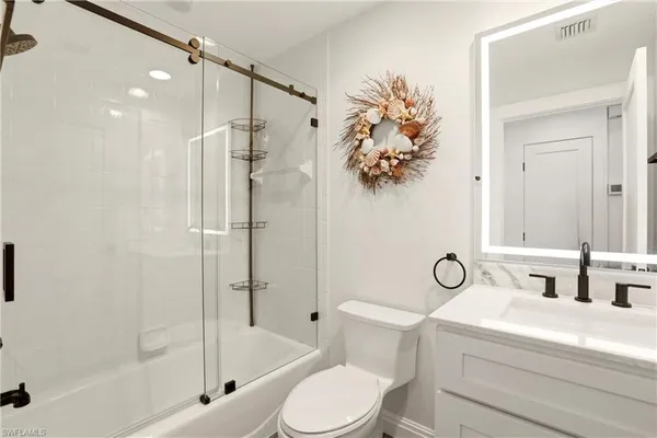 a bathroom with a shower sink mirror vanity and toilet