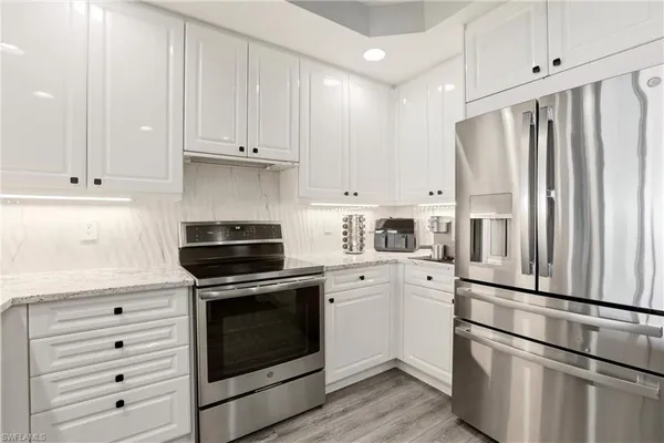 a kitchen with cabinets stainless steel appliances and wooden floor