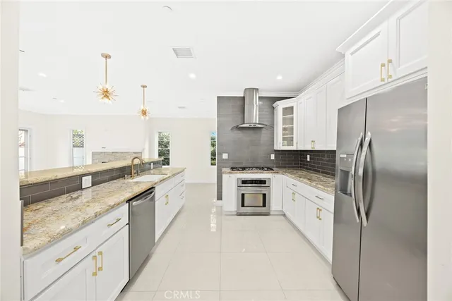 a large kitchen with stainless steel appliances kitchen island granite countertop a refrigerator a sink and white cabinets