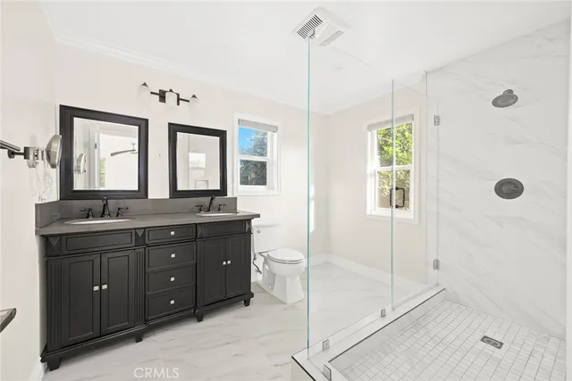a bathroom with a double vanity sink toilet and shower