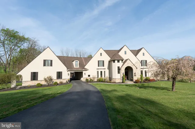 a view of white house with a big yard and large trees