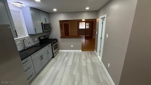 a kitchen with sink a refrigerator and wooden floor