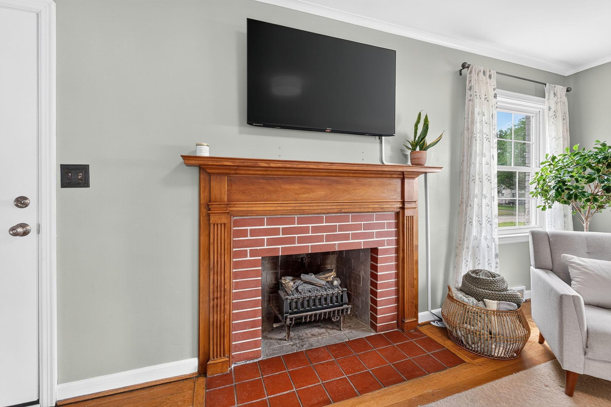 492 Wetmore Road Columbus, OH 43214 - Photo 14 of 55 Brick fireplace with a substantial wood mantelpiece, featuring an integrated grate, set against light gray walls with white crown molding