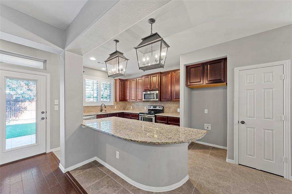 1901 Fair Parke Lane Wylie, TX 75098 - Photo 15 of 37 a kitchen with stainless steel appliances granite countertop a sink a microwave cabinets and wooden floor