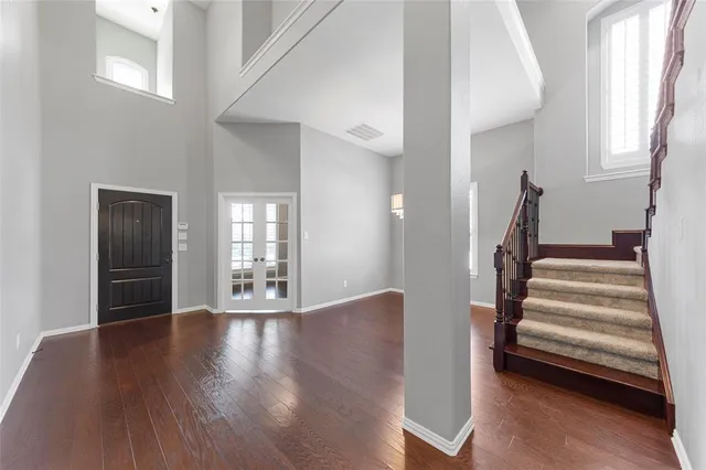 a view of an empty room with wooden floor and stairs