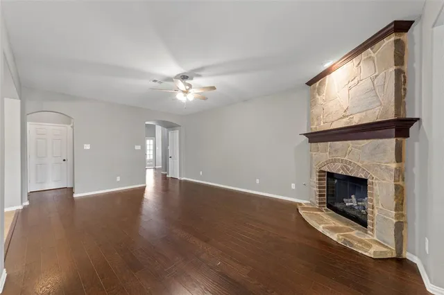 a view of an empty room with wooden floor fireplace and a window
