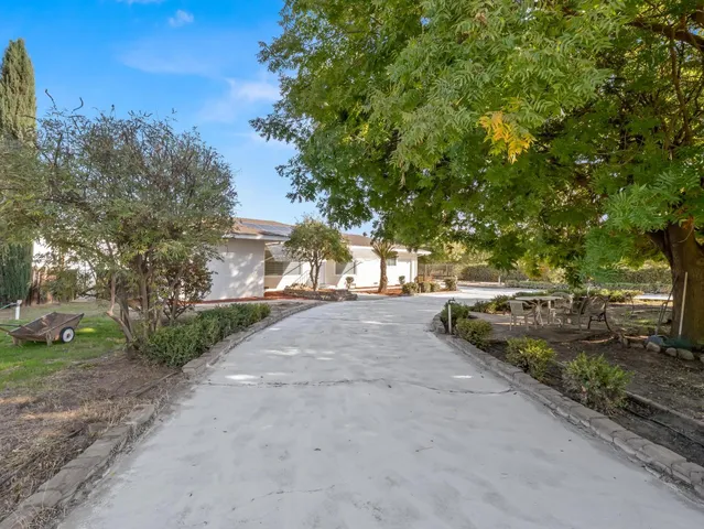 an empty room with wooden floor chandelier fan and windows