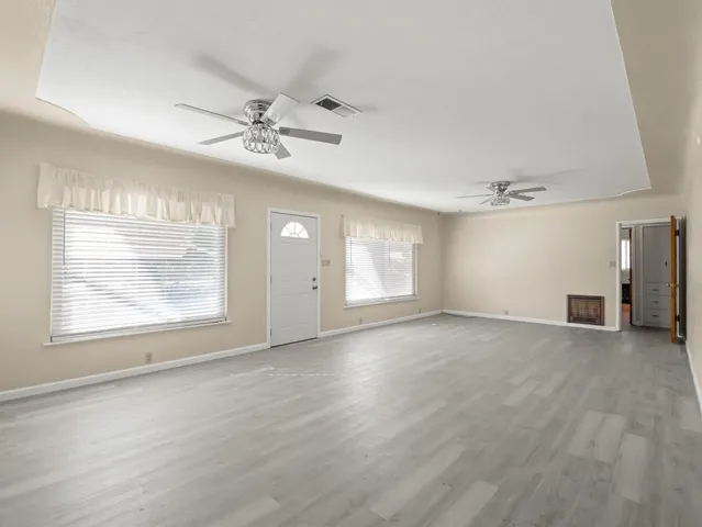 an empty room with windows and a ceiling fan