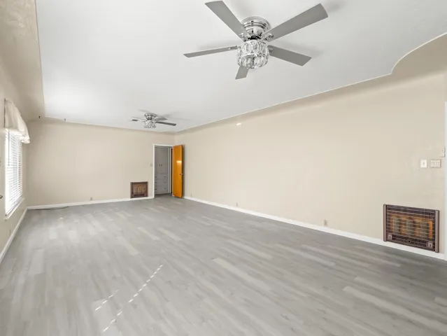 a large kitchen with a refrigerator and wooden floor