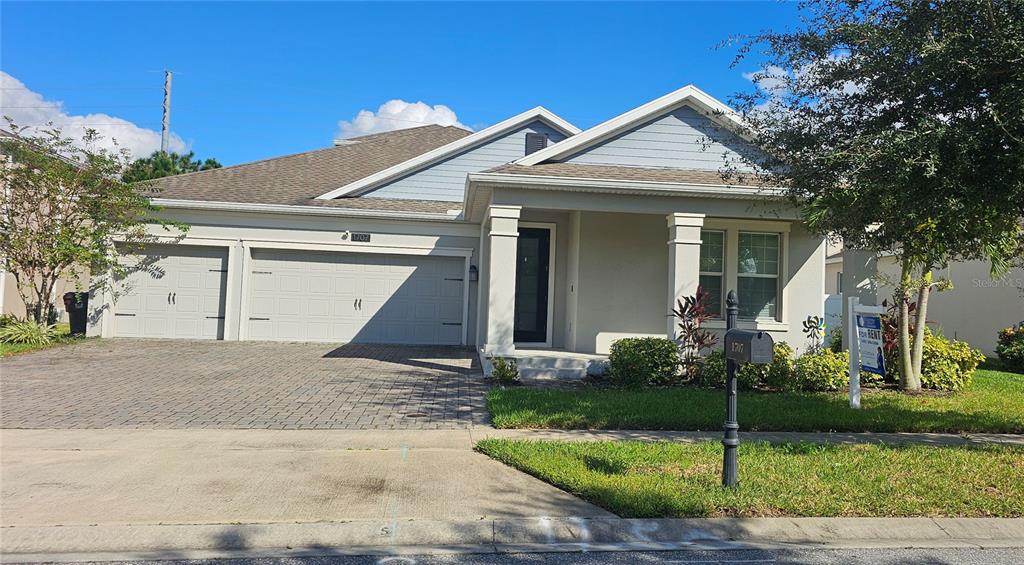 a view of a white house with a large windows and a yard with plants and large trees
