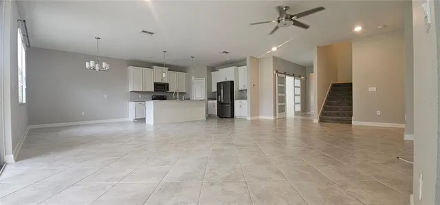 a large kitchen with stainless steel appliances kitchen island a large counter top and a refrigerator