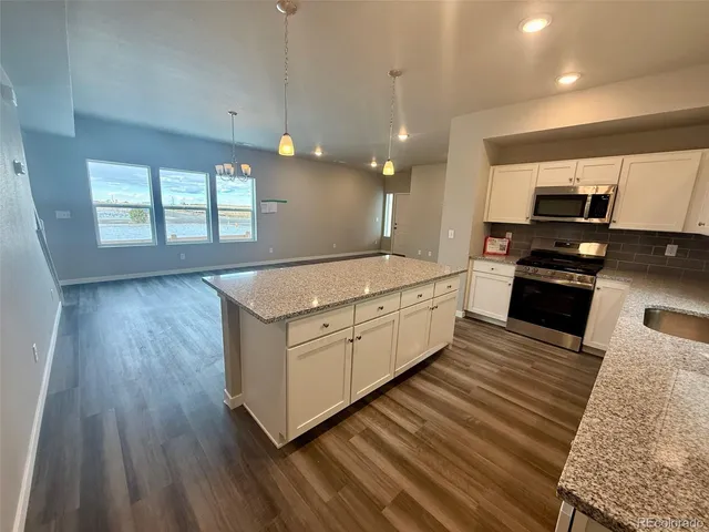 a large white kitchen with wooden floors and stainless steel appliances