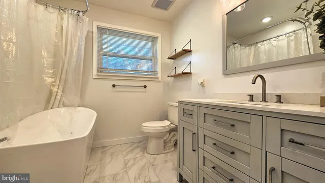 a bathroom with a toilet a sink a mirror a bathtub and vanity