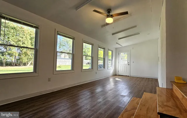 a view of an empty room with a window and wooden floor