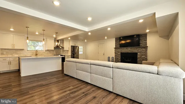 a living room with furniture a fireplace a flat screen tv and kitchen view