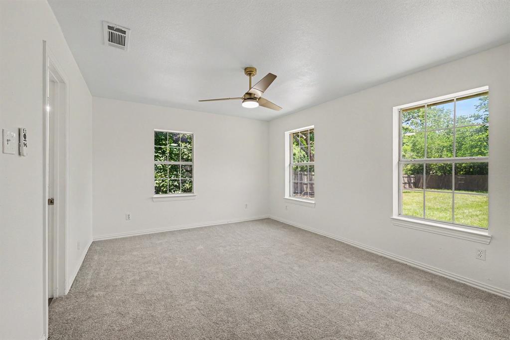 307 Dixon Street Terrell, TX 75160 - Photo 16 of 32 Carpeted room with white walls, two windows, and a ceiling fan with integrated lighting