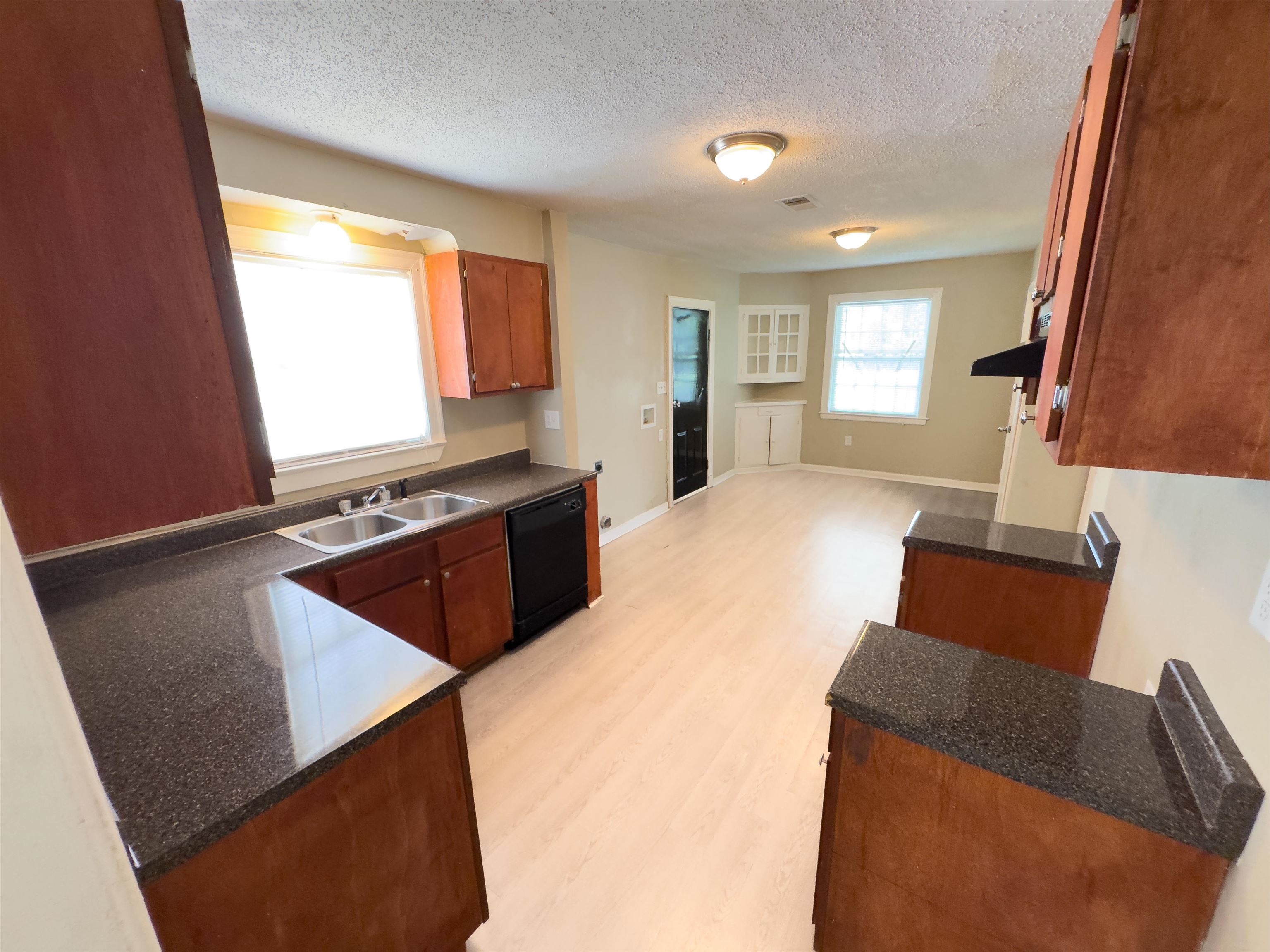 2703 Fizer Road Memphis, TN 38114 - Photo 11 of 19 Kitchen featuring dishwasher, a sink, light wood-style flooring, a textured ceiling, and brown cabinetry