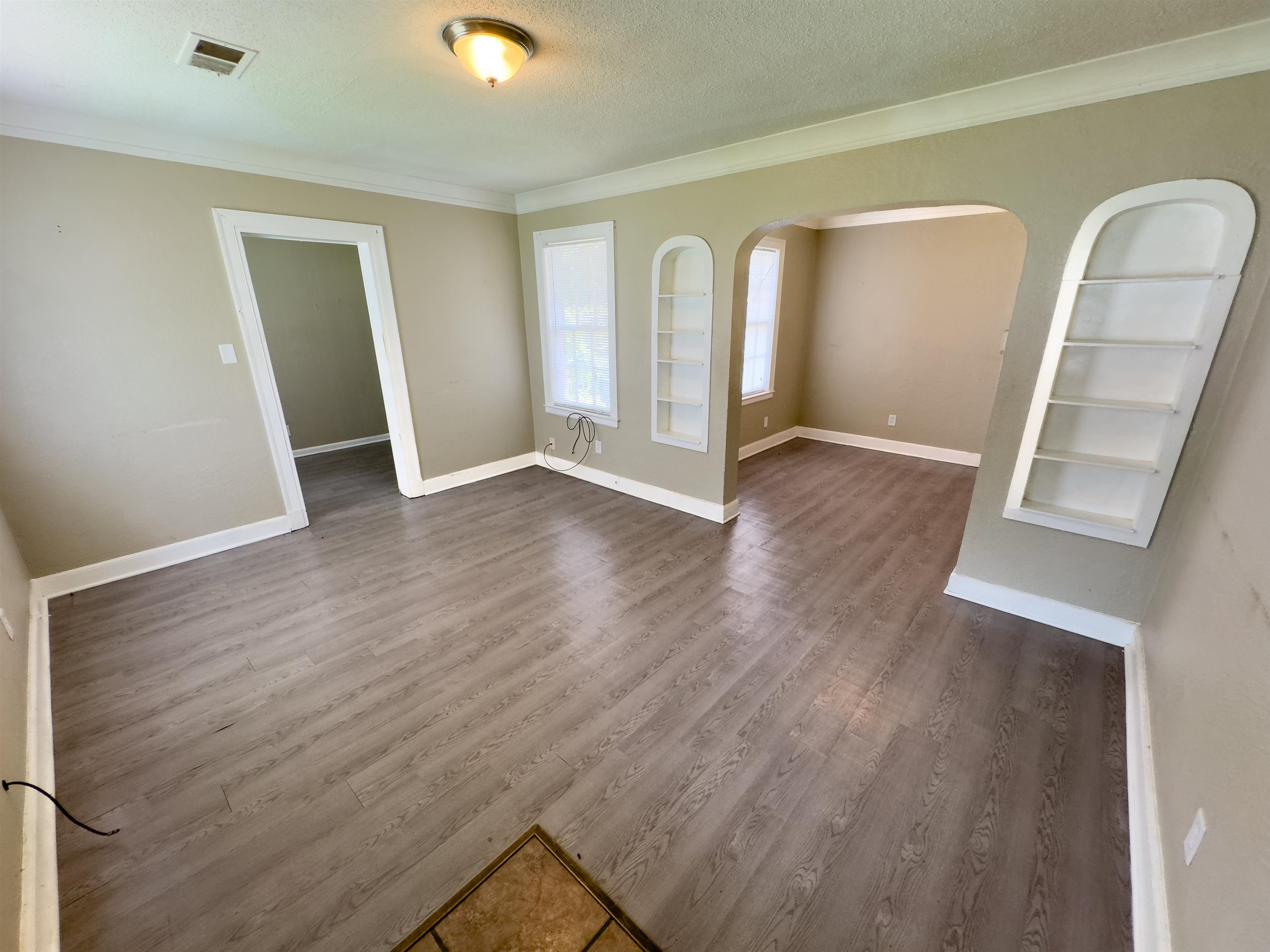 2703 Fizer Road Memphis, TN 38114 - Photo 8 of 19 Empty room with built in features, arched walkways, dark wood-style floors, crown molding, and a textured ceiling