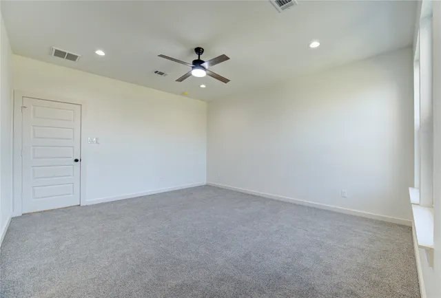 an empty room with a ceiling fan and a window