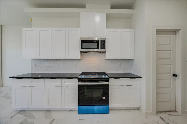 a kitchen with white cabinets and stainless steel appliances
